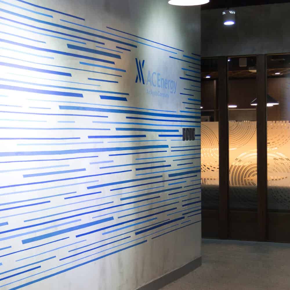 AC Energy branding with linear patterns on wall and glass signage, showcasing innovative visual identity design.