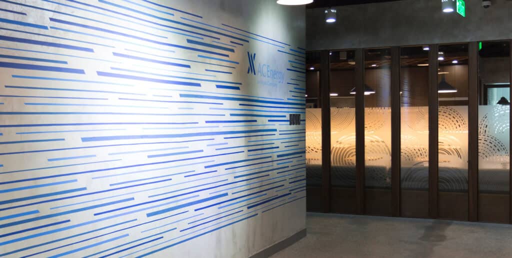 AC Energy branding with linear patterns on wall and glass signage, showcasing innovative visual identity design.