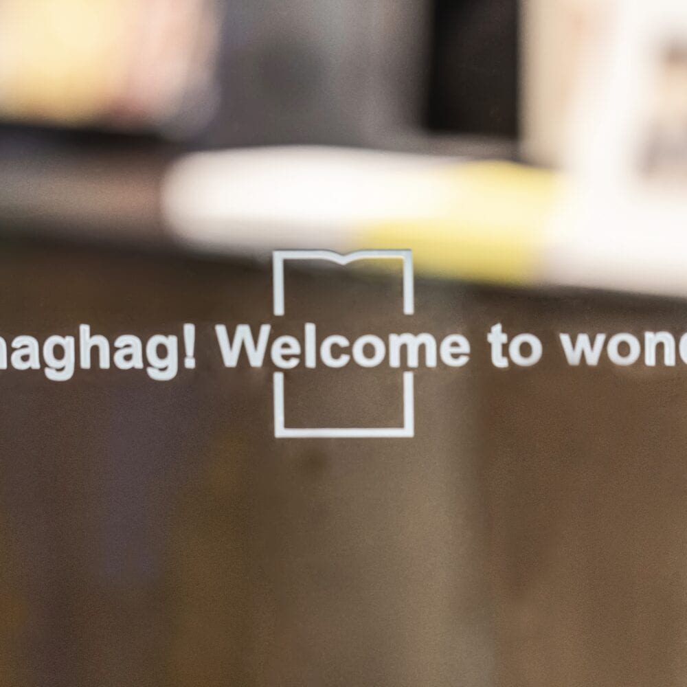 Glass door with 'Hello, maghag! Welcome to wonderland!' text, reflecting engaging brand identity focus.