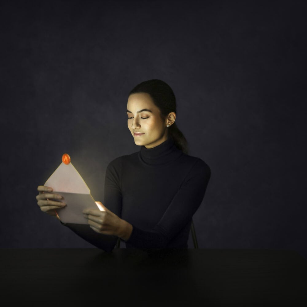 Woman in dark attire opens a glowing envelope with red wax seal, highlighting unique branding and design elements.