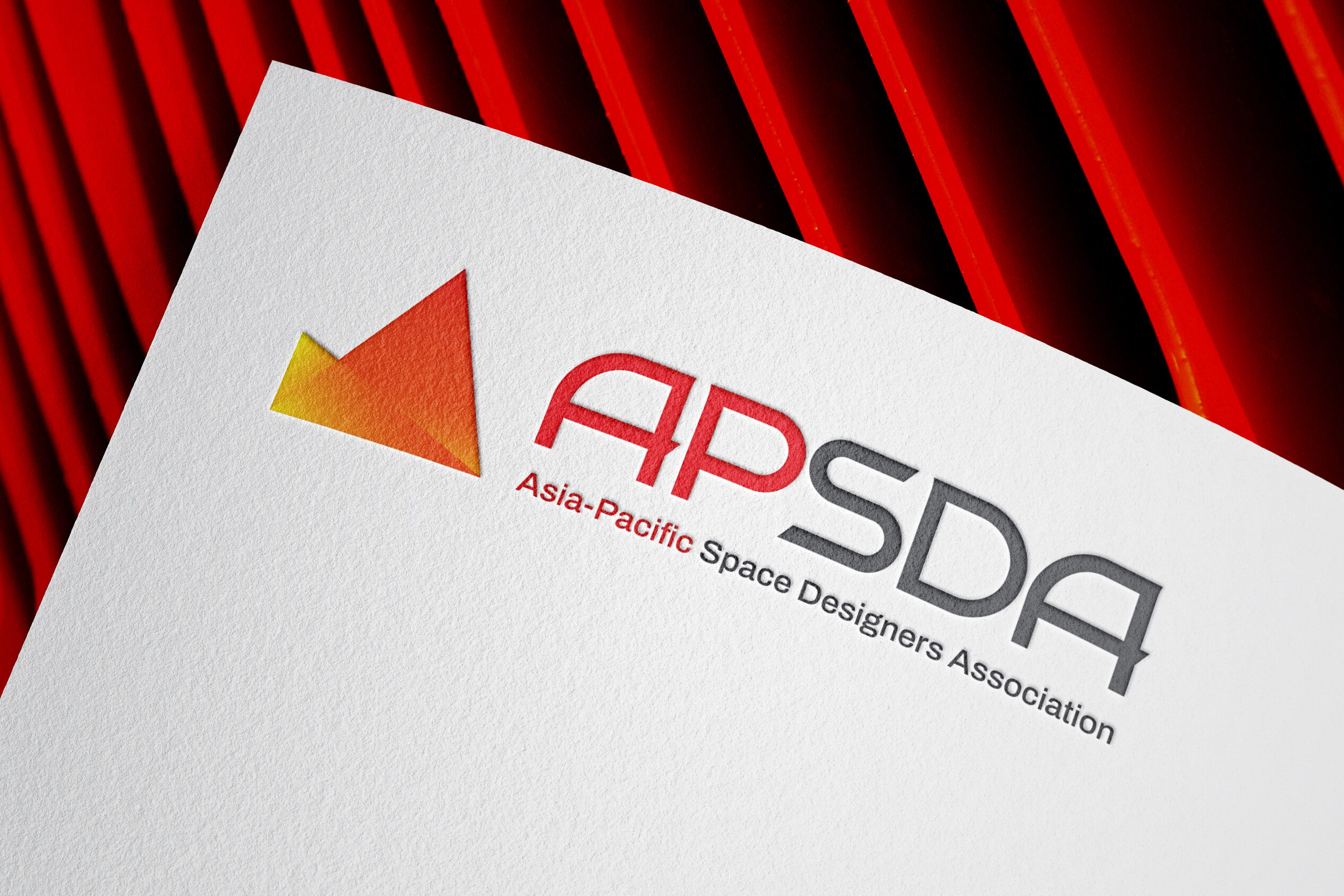 APSDA branding on textured paper with red geometric background, showcasing brand identity and visual design.