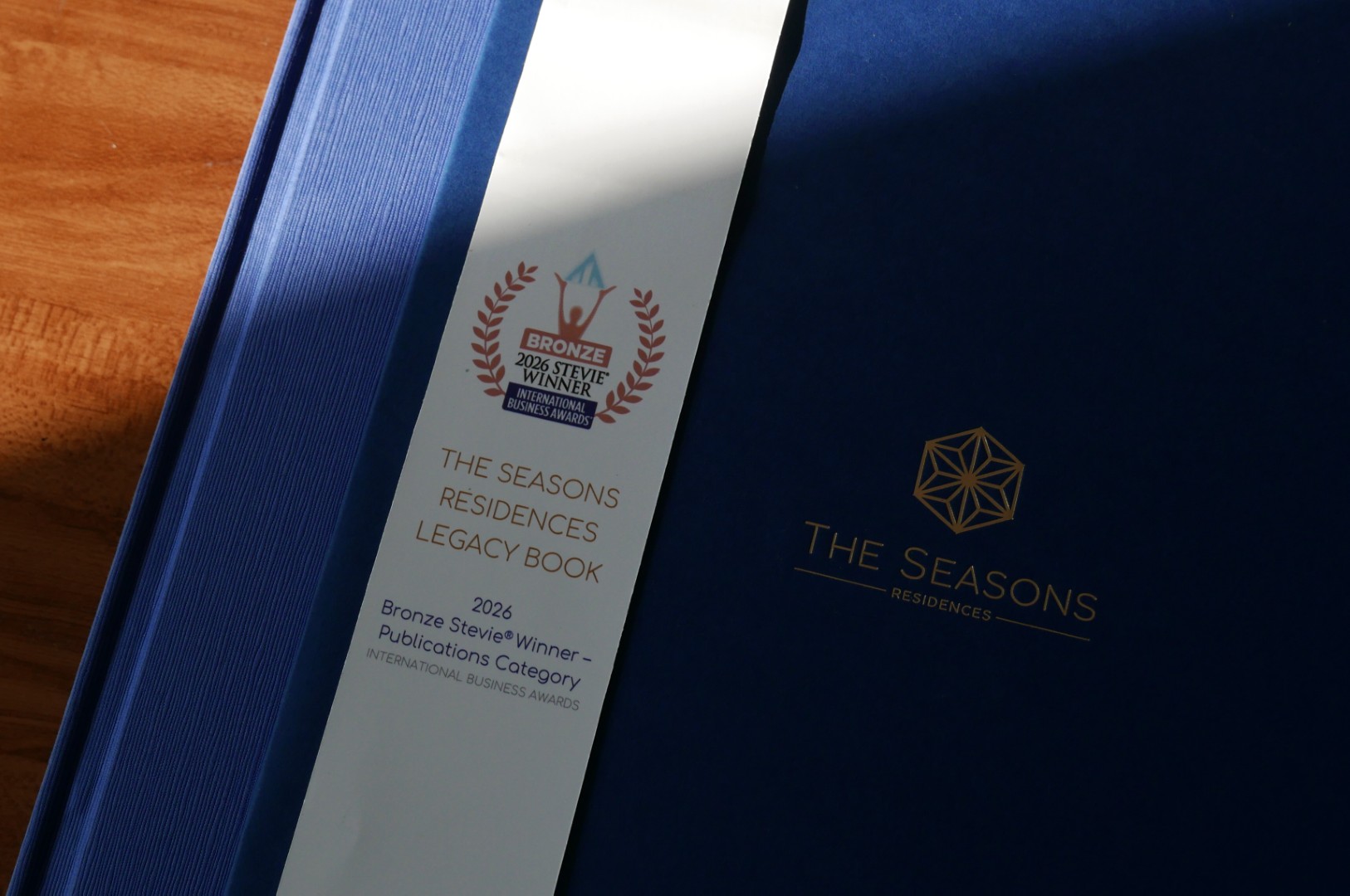 The Seasons Residences Legacy Book with Bronze Stevie Award for Publications, showcasing branding and visual identity design.