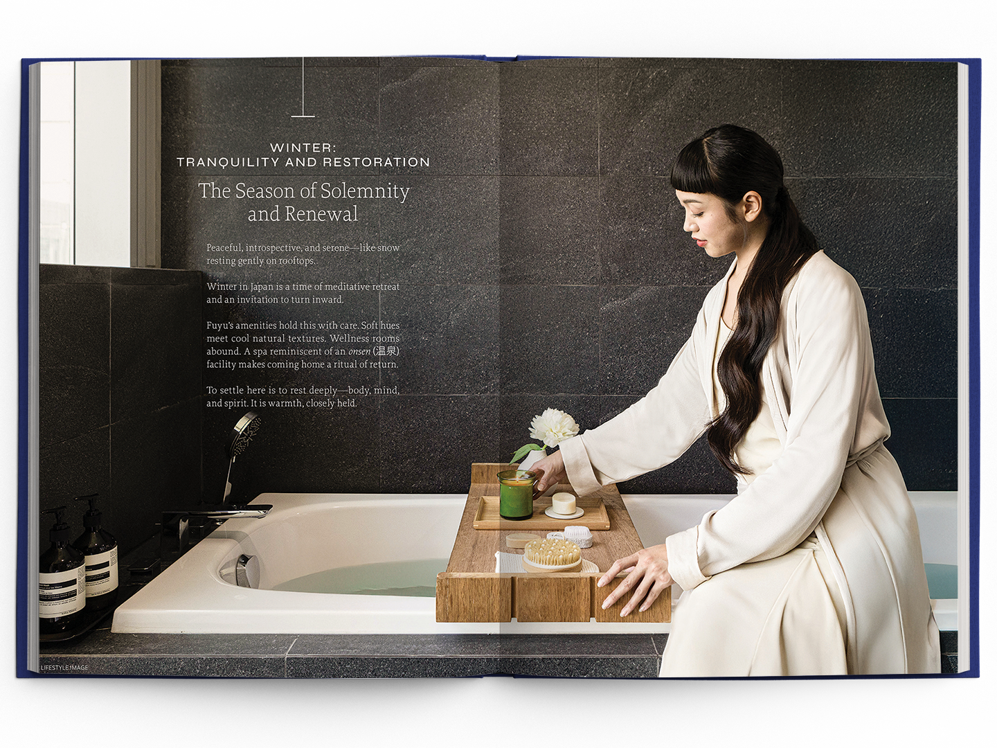 Woman in a robe sitting by a bathtub with a wooden tray, promoting tranquility and renewal in spa-like setting.