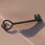 Antique key casting a shadow on a textured surface, symbolizing unlocking design potential in branding and visual identity.