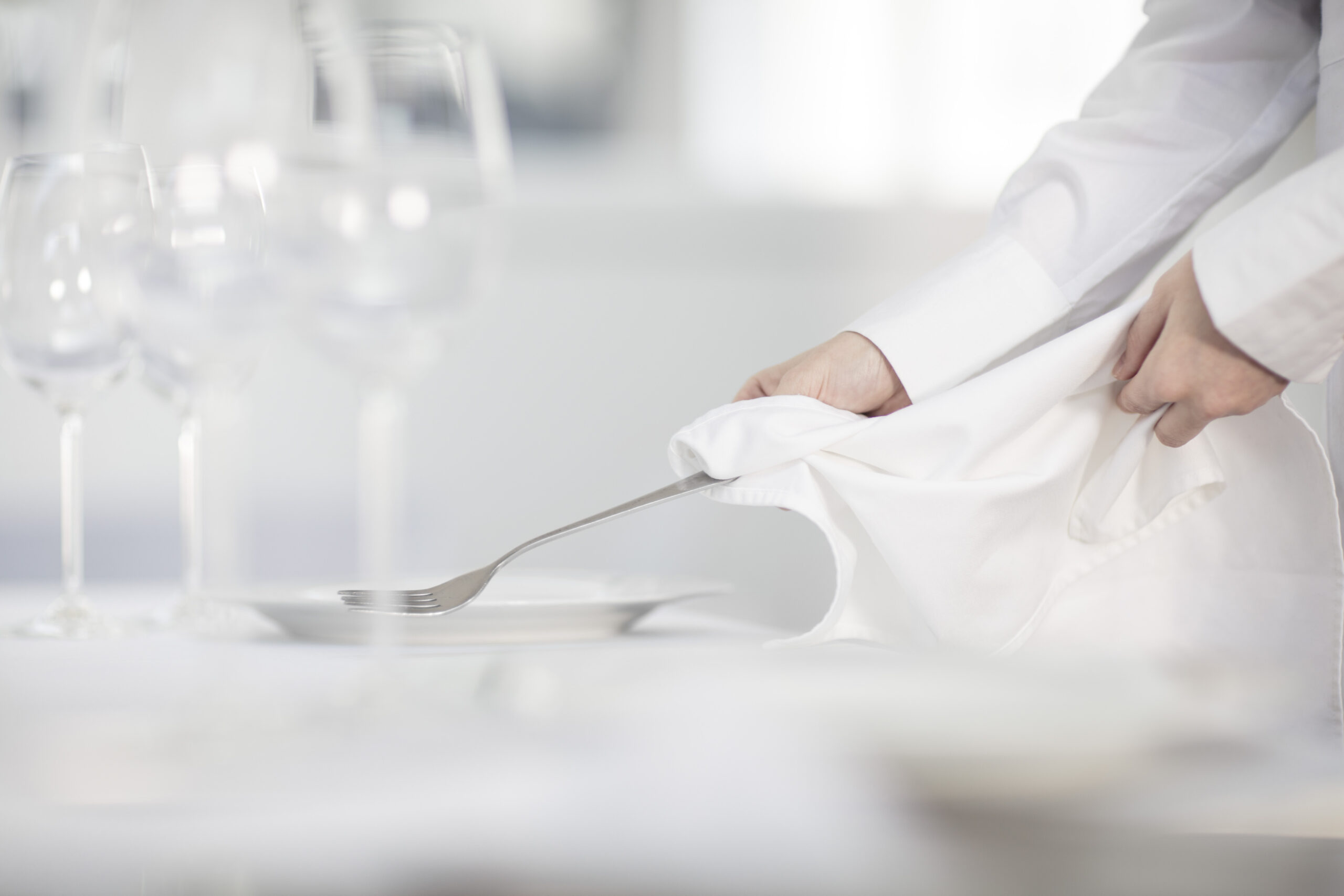 Restaurant table set with a white napkin, cutlery, and wine glasses.