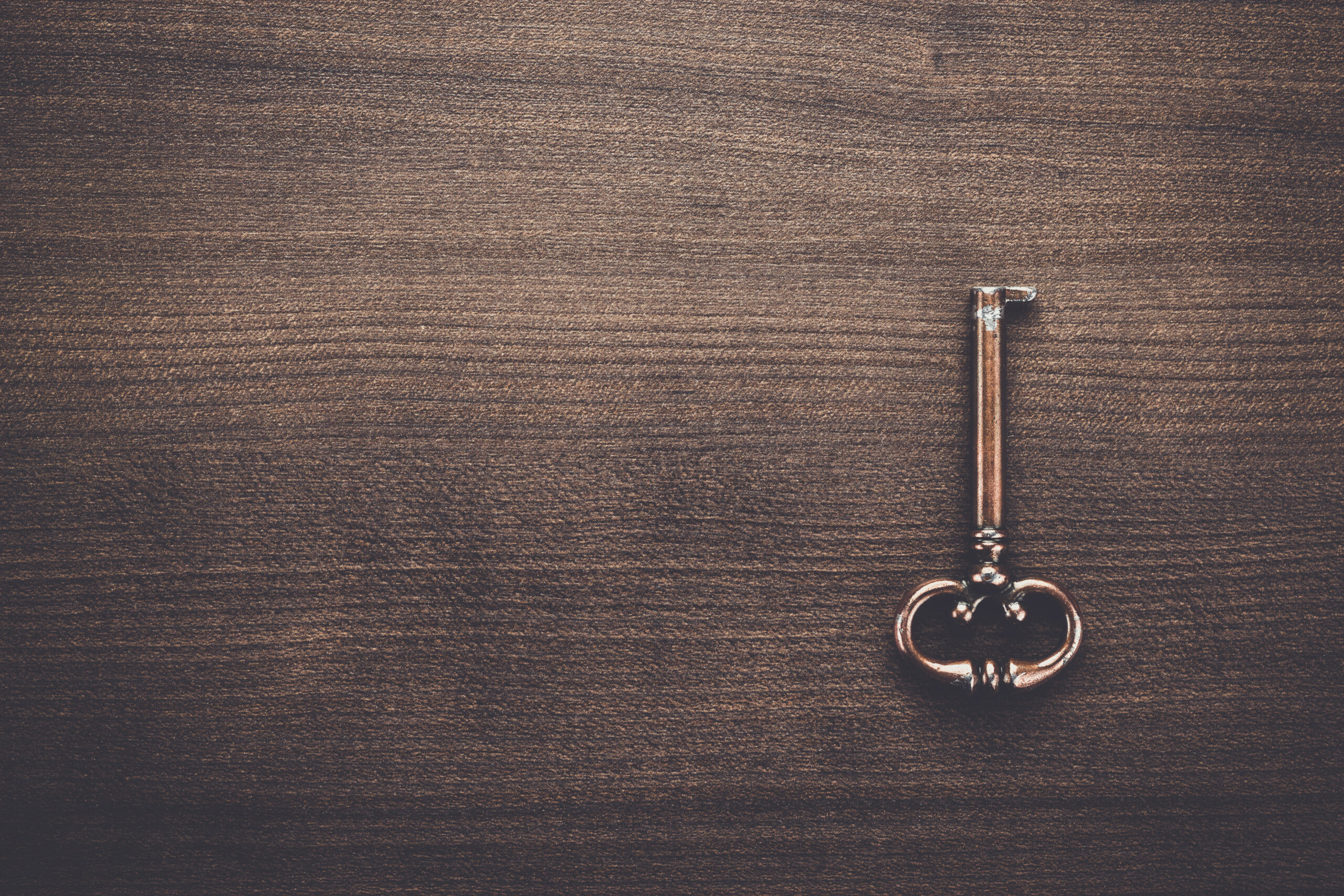 Vintage brass key resting on a wooden surface.